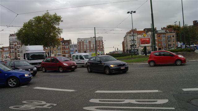Nog op het Meiserplein: de vrachtwagen op de achtergrond heeft de rotonde verticaal overgestoken om de Leuvensesteenweg in te rijden. Volgens de verkeersregels moet je natuurlijk via het uiterst rechter baanvak rijden om rechts af te slaan. Verschillende personenwagens verhinderen dat. Ondertussen zie je links op de voorgrond een blauwe personenwagen een "concurrent" die rechts wil afslaan de pas afsnijden...