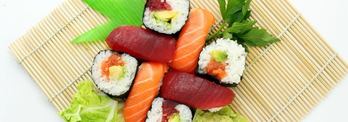 Sushi met zalm, rode vis en groente op een bamboematje.