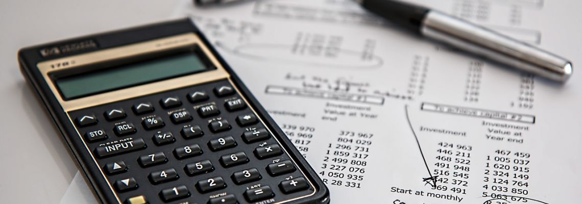 Rekenmachine en pen op papieren met financiële cijfers.