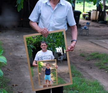 Een man houdt een kader vast met daarin een jongere man die een kader met een kind vasthoudt.