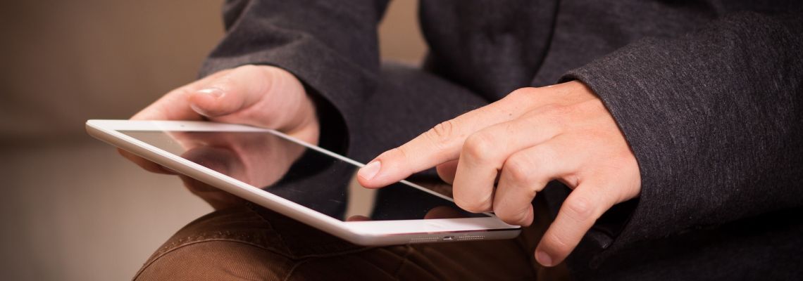 Iemand houdt een tablet vast en raakt het scherm aan.