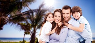Twee volwassenen en twee kinderen omhelzen elkaar bij het strand.