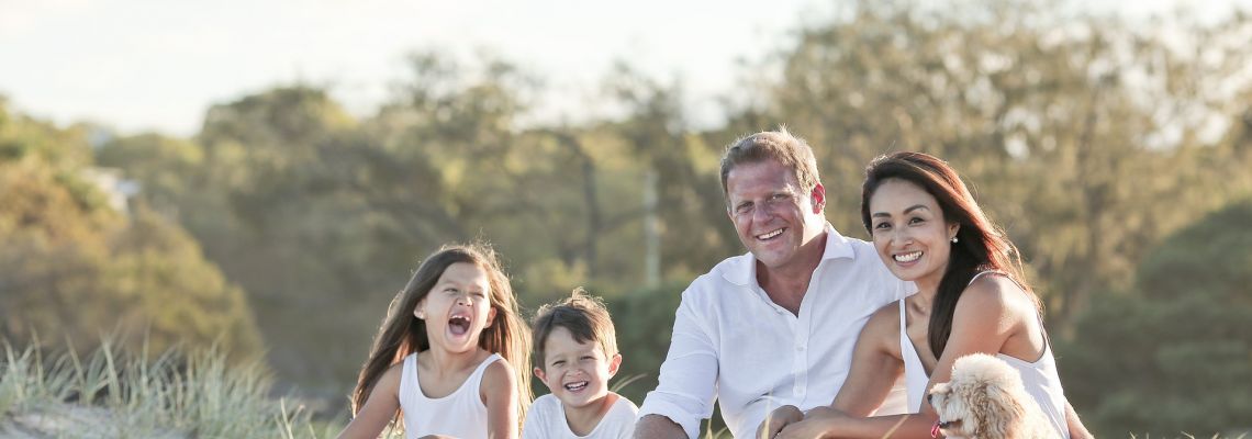 Twee volwassenen en twee kinderen zitten samen buiten in het gras.
