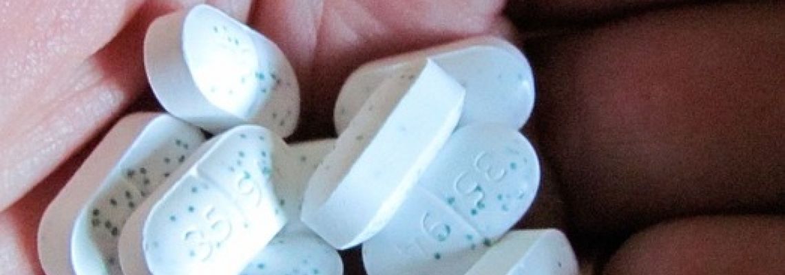 Een hand met witte, gespikkelde tabletten.