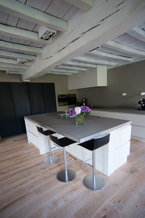 Er is gebruik gemaakt van wat aanwezig is in het bestaande gebouw om een mix te krijgen van oud en nieuw.De balken en het houten plafond zijn gemoderniseerd door ze grijs te schilderen.De keuken is heel open en minimalistisch gehouden.Uitvoering Alkas.