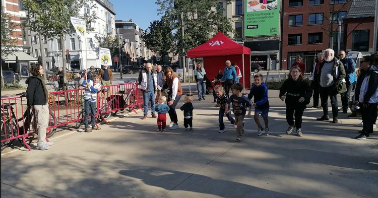 Grootouders en kleinkinderen lopen samen een wedstrijdje op een plein.