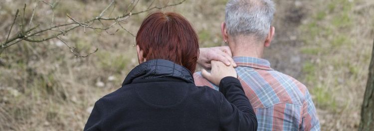 Een vrouw legt haar handen op de schouder van een oudere man.