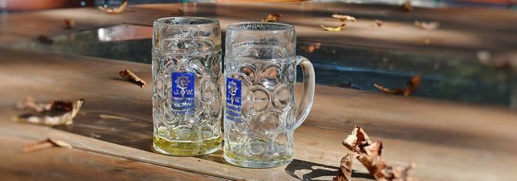 Twee bijna lege bierpullen op een houten tafel met dorre bladeren.