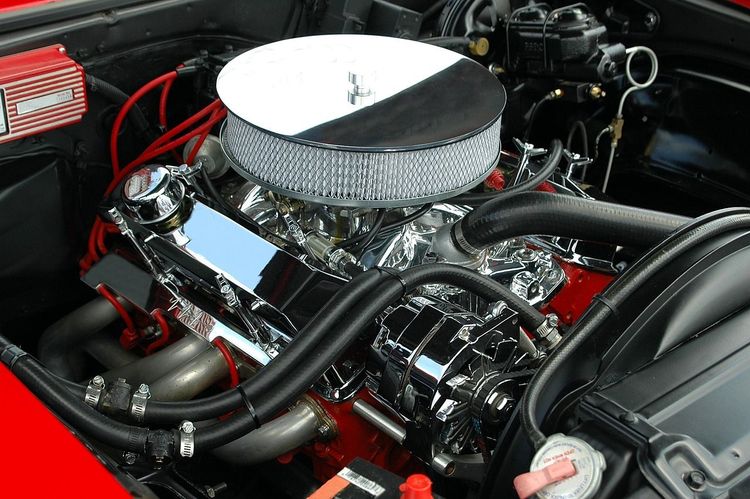 Blinkende motor met verchroomde onderdelen onder de open motorkap van een auto.