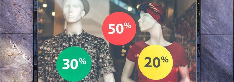 Etalage met aangeklede paspoppen en stickers met 20, 30 en 50 procent korting.