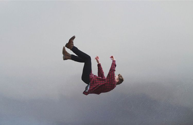 Een man valt achterover door de lucht, met zijn benen omhoog en zijn armen uitgestrekt.