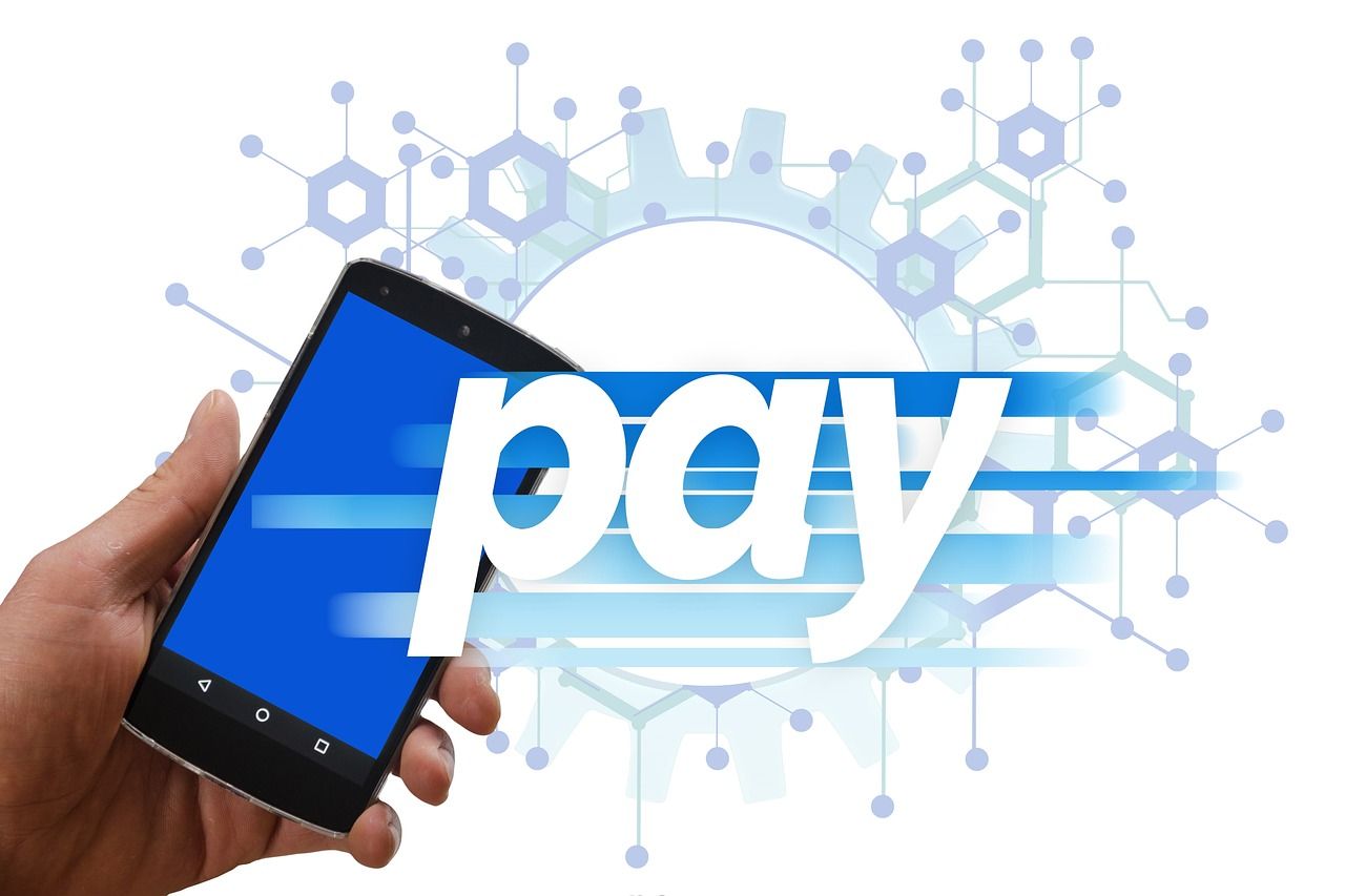 Een hand houdt een smartphone vast met het woord ‘pay’ groot in beeld.