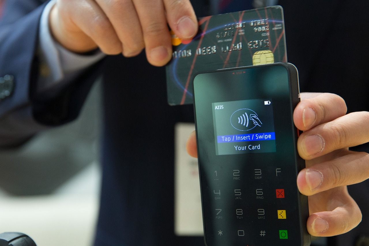 Een bankkaart wordt boven een betaalterminal gehouden om contactloos te betalen.