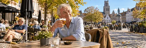 Oudere man geniet van een pint op een zonnig terrasje, omringd door goudgele herfstbladeren.
