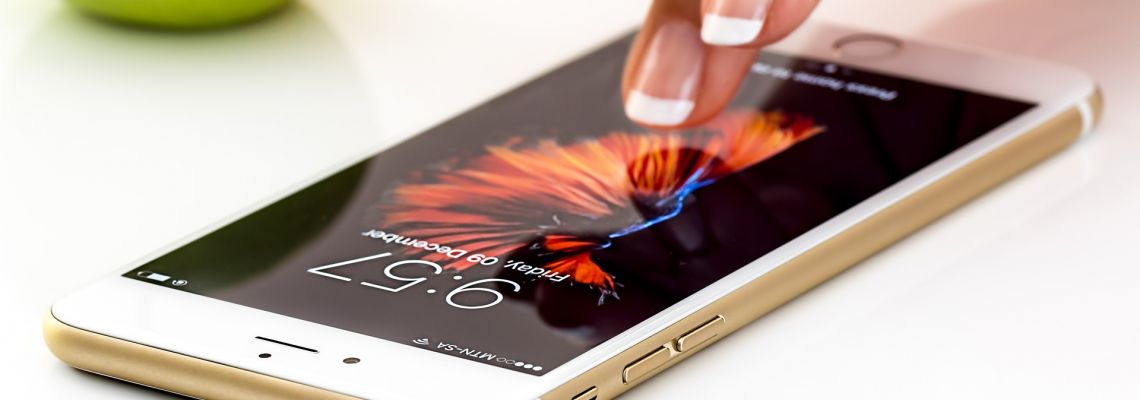 Een vinger raakt het scherm aan van een smartphone die op tafel ligt.