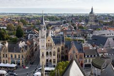 Zicht over een stadsplein met historische gebouwen, spitse torens en terrassen.