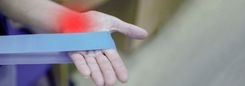 Hand met een oefenband en een rood gemarkeerde pijnlijke pols.
