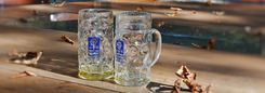 Twee bijna lege bierpullen op een houten tafel met dorre bladeren.