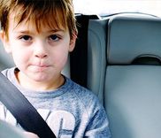 Kind zit met de veiligheidsgordel vast op de achterbank van een auto.
