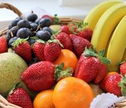 Een mand vol aardbeien, bananen, druiven, peren en sinaasappels.