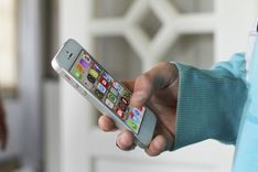 Een hand bedient een smartphone met verschillende apps op het scherm.
