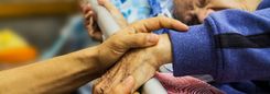 Een hand houdt de arm van een oudere persoon zachtjes vast.