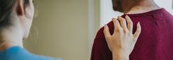 Een vrouw legt haar hand op de schouder van een man.