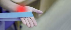 Een hand oefent met een blauwe weerstandsband, met een rode markering ter hoogte van de pols.