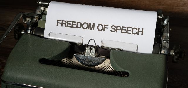 Een oude typemachine met een blad waarop in het Engels ‘vrijheid van meningsuiting’ staat.