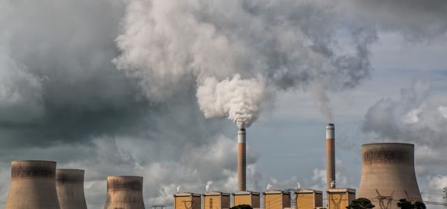 Dikke rookpluimen boven schoorstenen en koeltorens van een centrale.